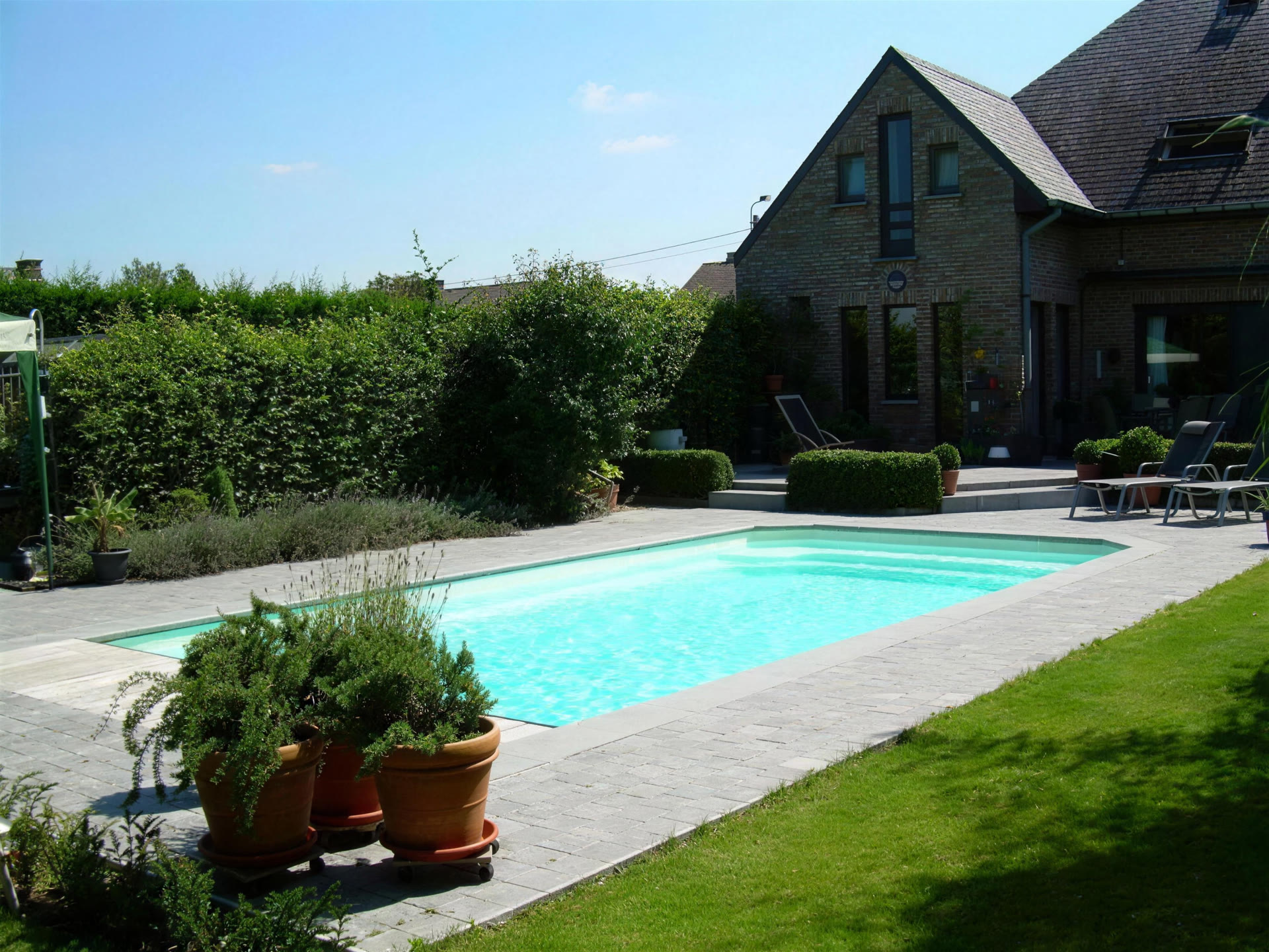 Piscine rectangulaire avec pelouse et maison en pierre