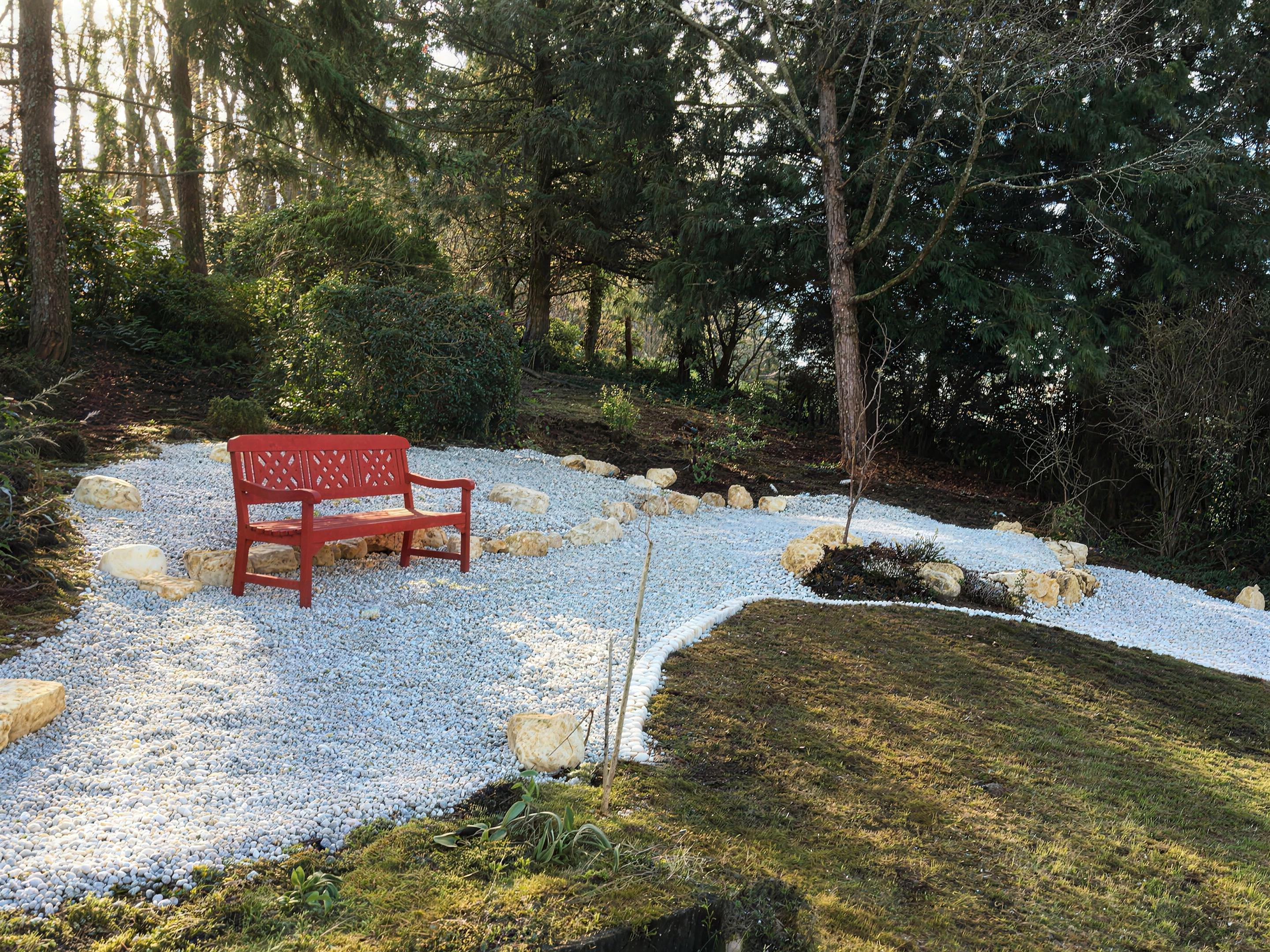 Jardin zen avec banc rouge et gravier blanc