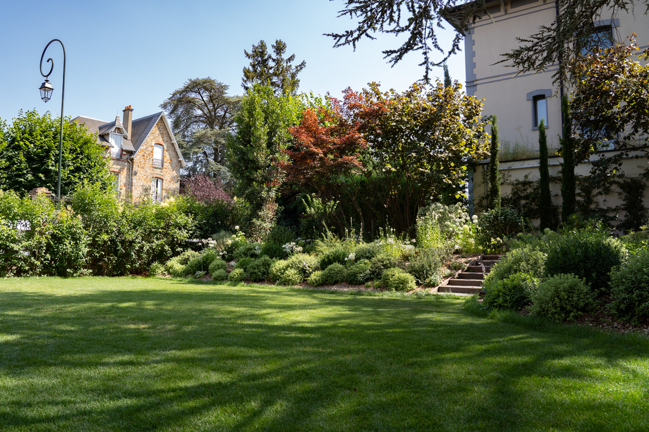 Jardin architectural d'une demeure : pelouse soignée, massifs structurés et arbres matures, Hauts-de-Seine