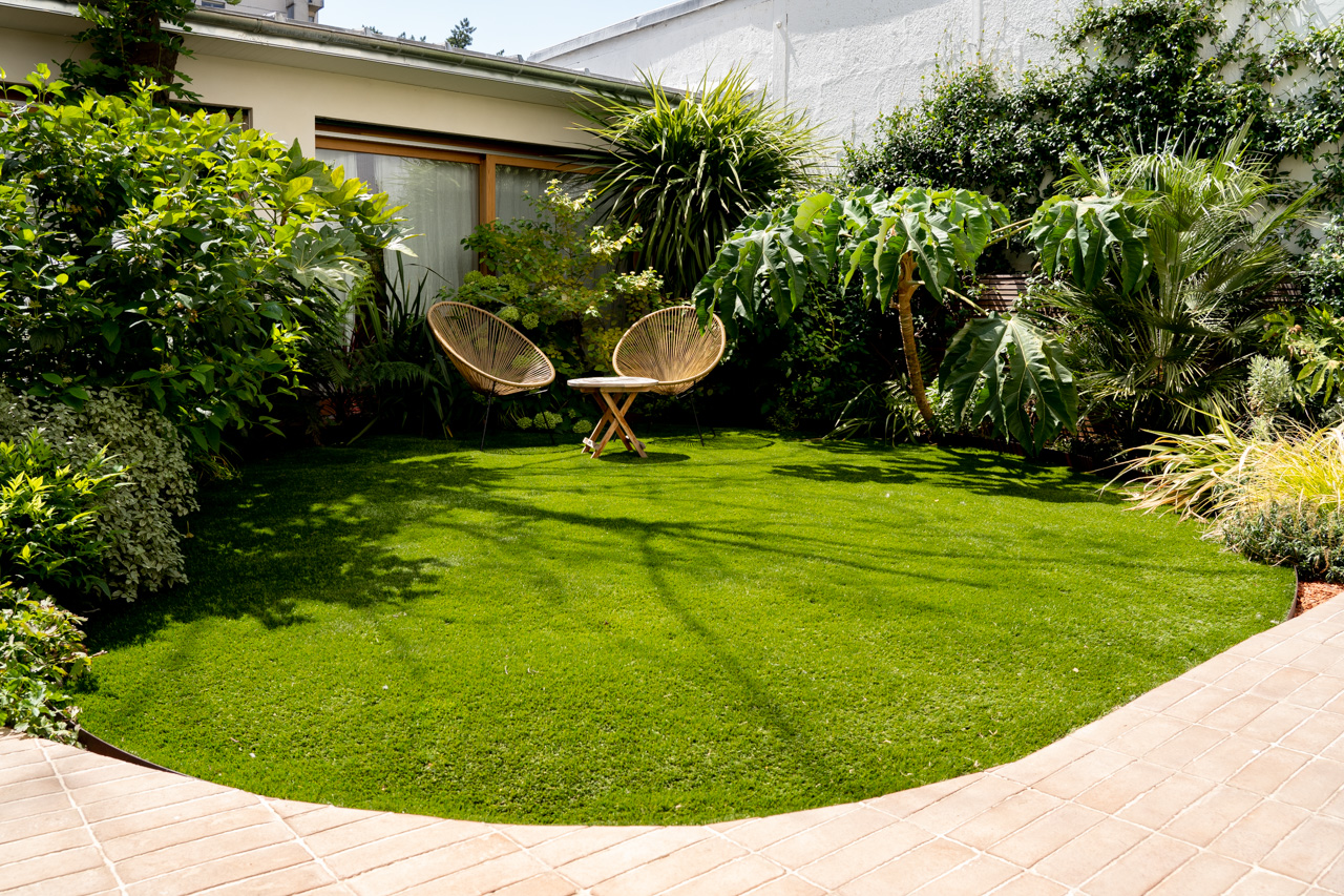 Jardin pavillonnaire avec pelouse circulaire et fauteuils en rotin