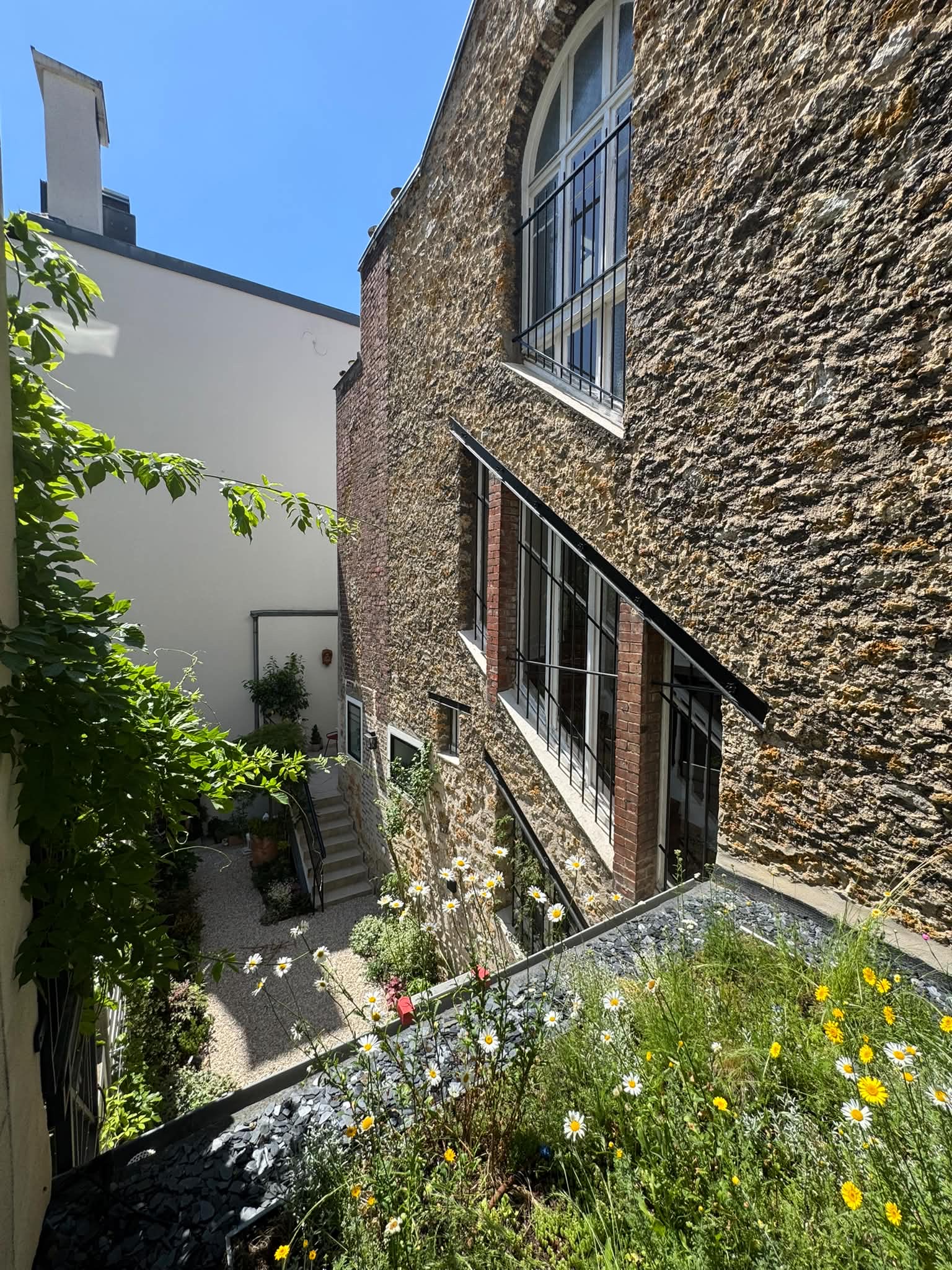 Cour pavée et mur de pierre fleuri