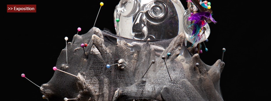 Sculpture mixte verre et textile constellée d'épingles colorées, exposée sur fond noir
