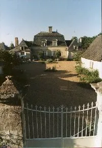 Le manoir des Chais de Rousson et sa cour ombragée, vus depuis la grille d'entrée à la lumière du soir.