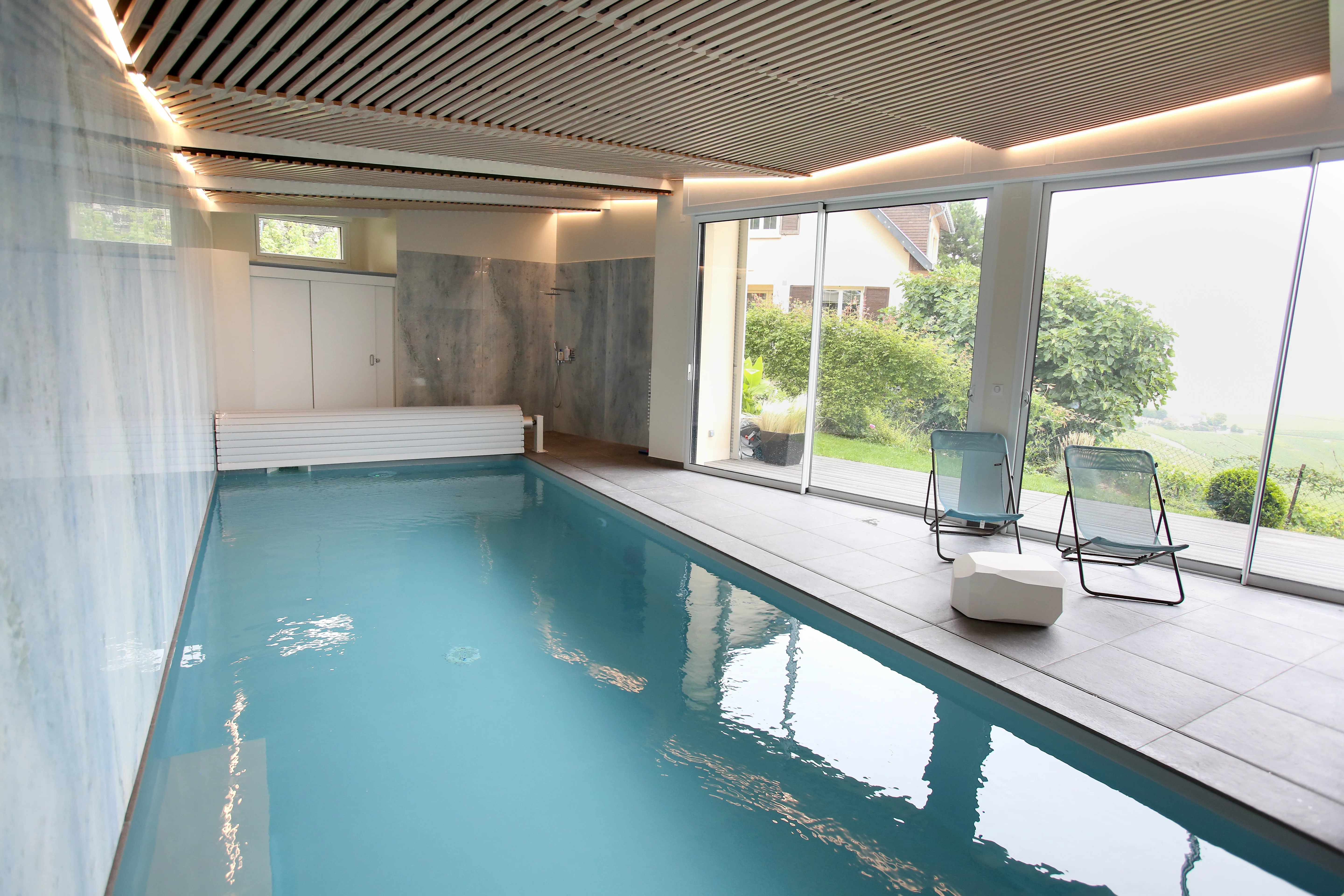 Piscine intérieure avec eau turquoise et grandes baies vitrées