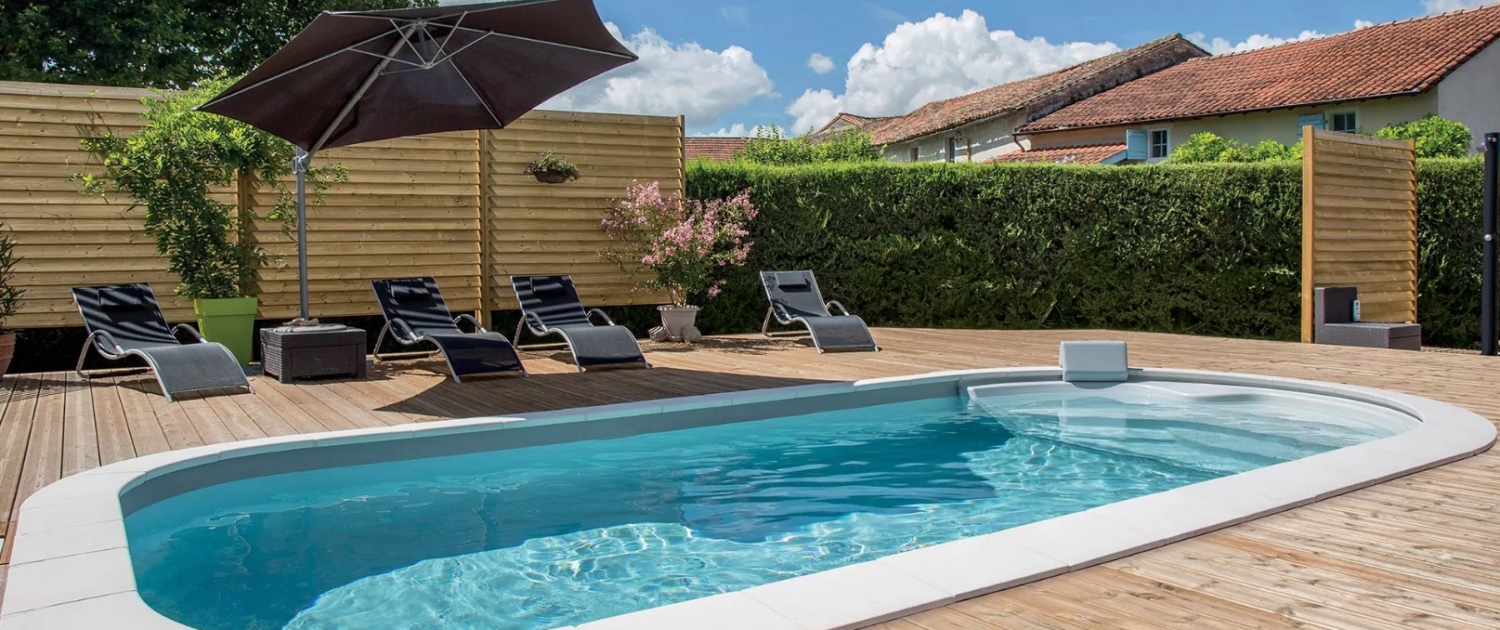 Piscine enterrée avec terrasse bois, parasol et bains de soleil, maison du Gers