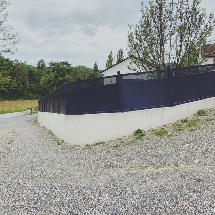 Brise-vue en aluminium gris anthracite posé sur un muret en béton
