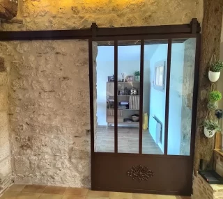 Porte verrière coulissante en acier sur un mur en pierre ancienne