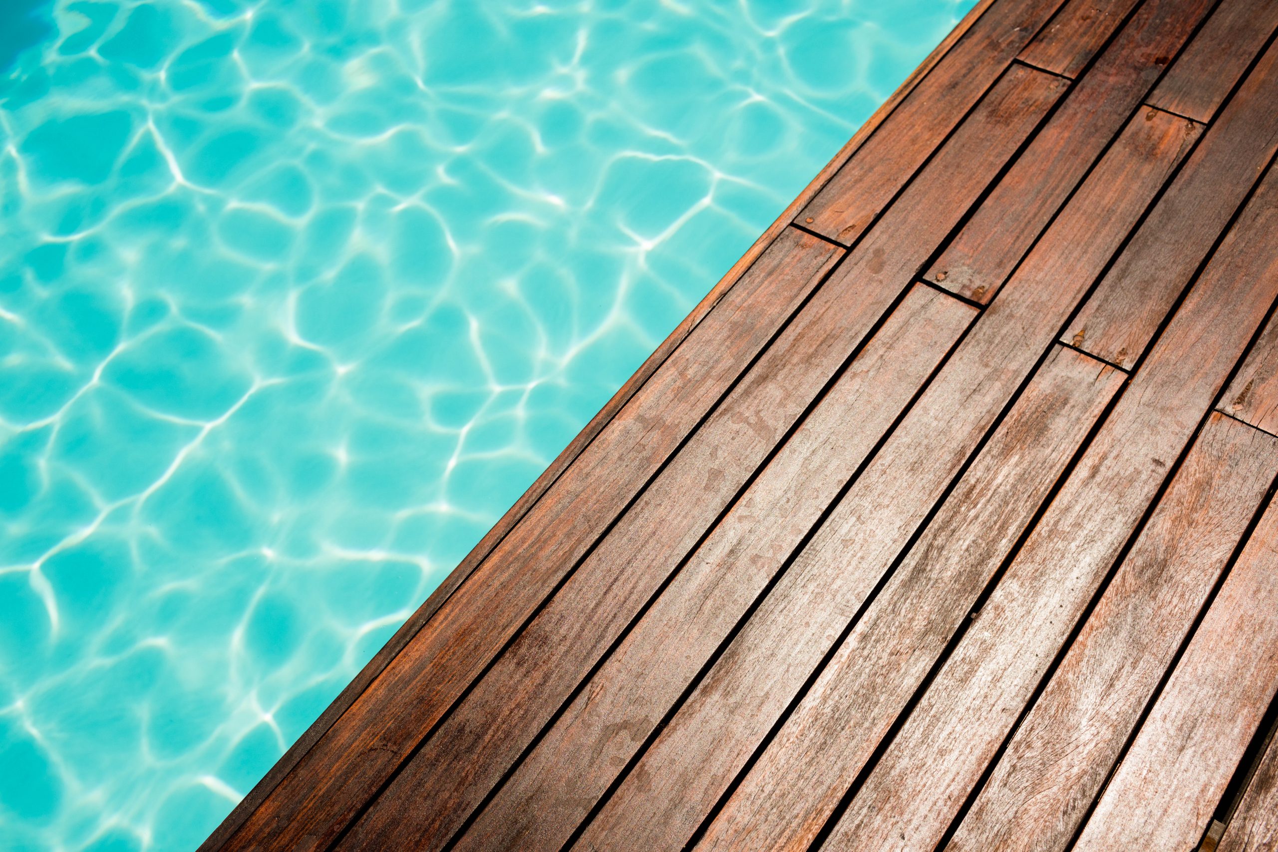 Piscine avec terrasse en bois, eau turquoise