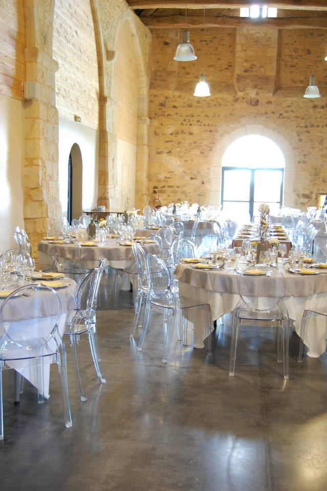 La grande salle de la grange dressee pour un repas de mariage sous la charpente