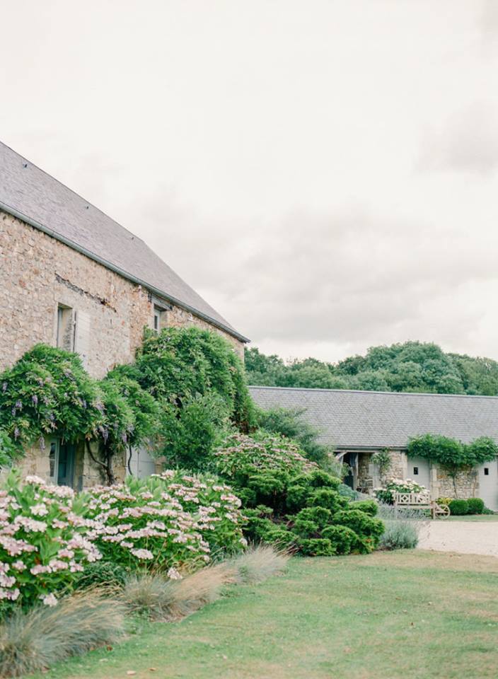 Facades de pierre couvertes de glycine et hortensias dans la cour