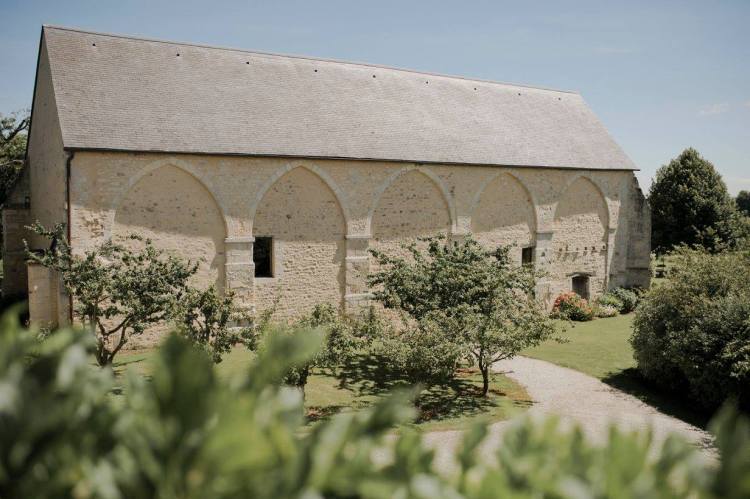 La grange du XIVe siecle vue de l'exterieur, ses arches de pierre et son jardin