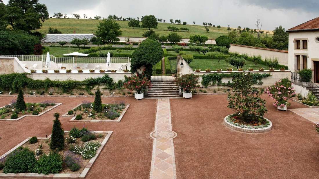 Le jardin à la française du château vu de haut, ses parterres géométriques, sa pièce d'eau et les collines de Lorraine à l'horizon.