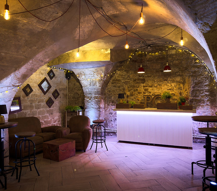 La grande cave voûtée du Paris Clandestin, pierre apparente, guirlandes et bar éclairé