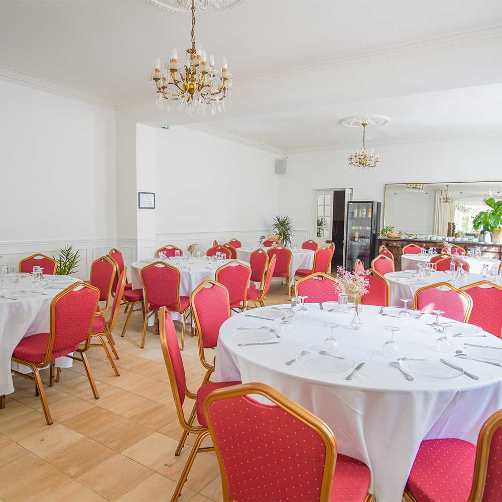 Salon de réception élégant aux lustres en cristal, tables dressées et chaises rouge et or, pour un repas plus intime