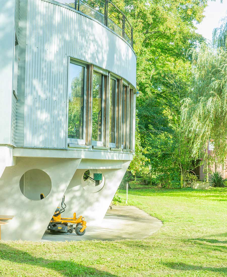 Bâtisse à l'architecture singulière, façade galbée parmi les arbres et la lumière filtrée