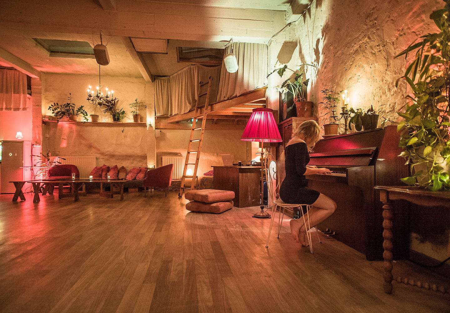 Coin piano &eacute;clair&eacute; aux bougies, mezzanine et plantes sur les murs de pierre