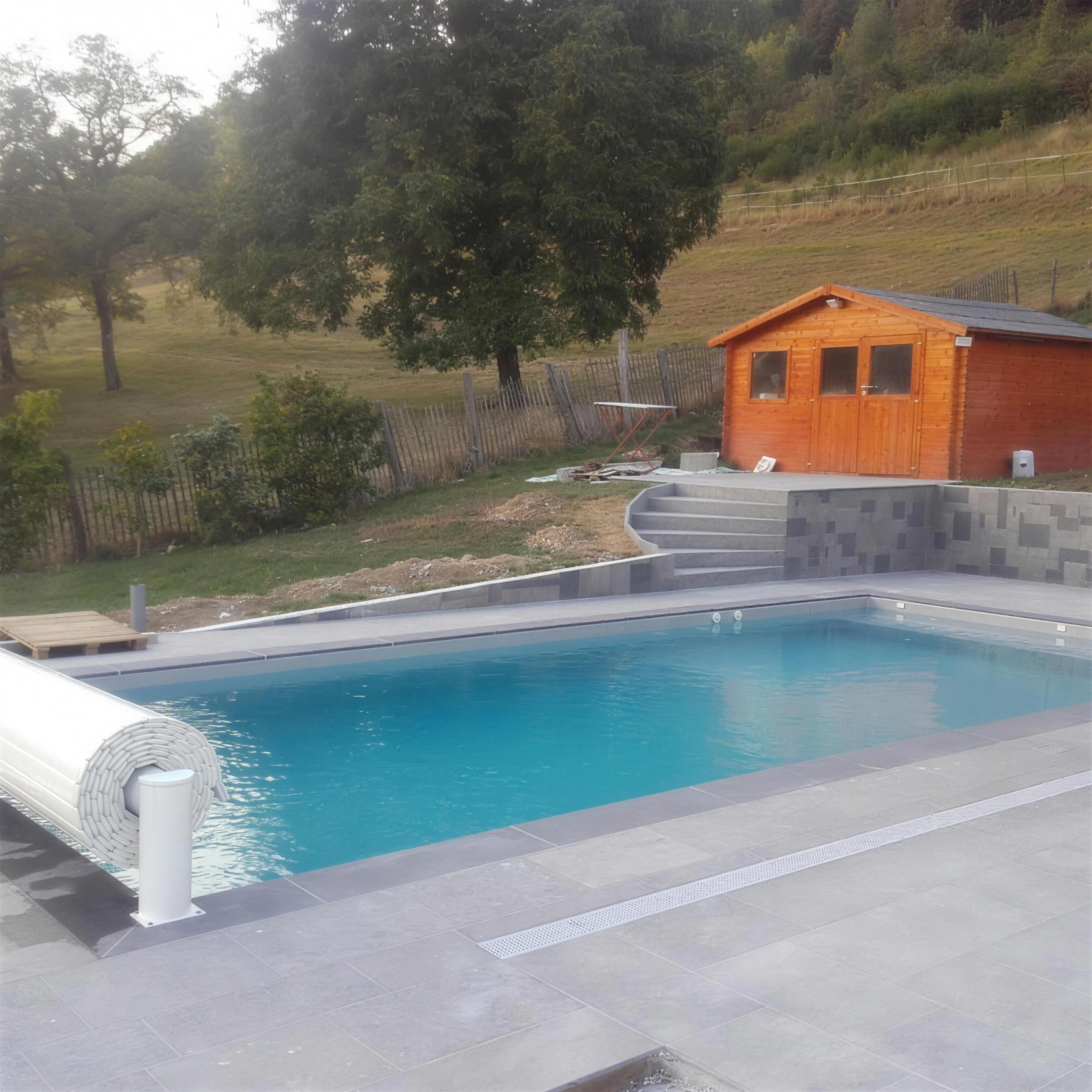 Piscine avec volet et chalet en fond de jardin