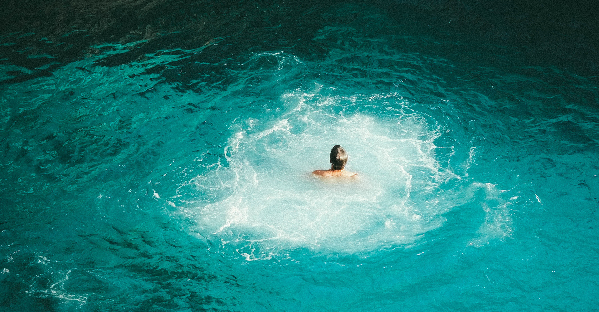 Vue aérienne d'un nageur dans une eau turquoise profonde