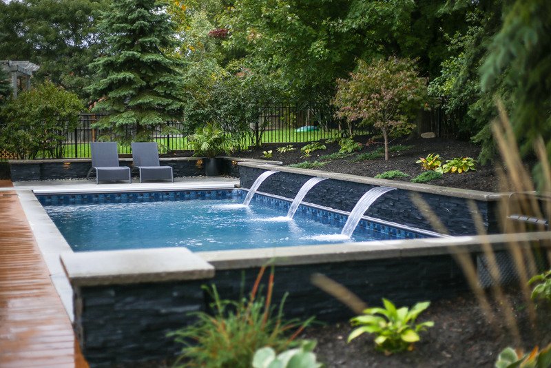Piscine avec lames d'eau en pierre et cascades, jardin paysager