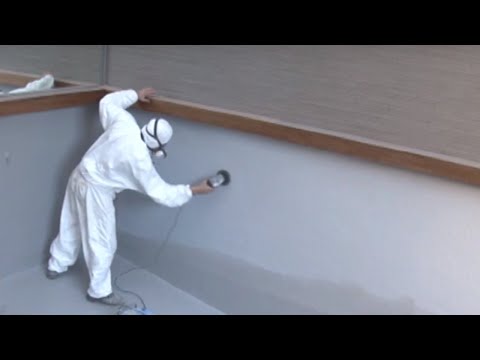 Applicateur en combinaison projetant la résine polyester sur la paroi d'un bassin