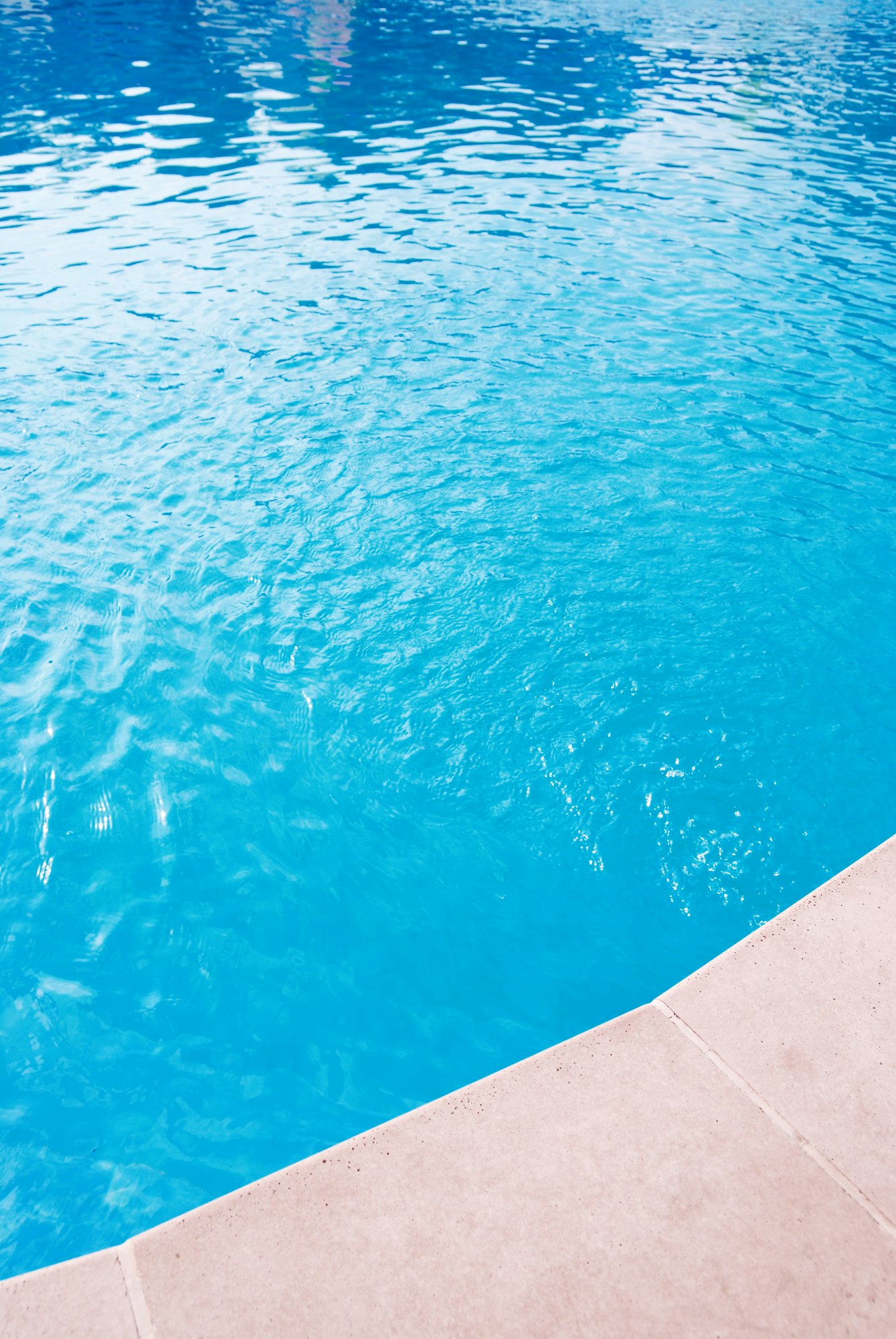 Détail de l'eau turquoise et de la margelle d'une piscine