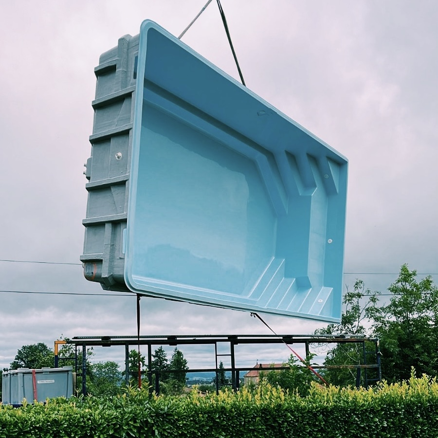 Coque polyester soulevée par une grue lors de l'installation