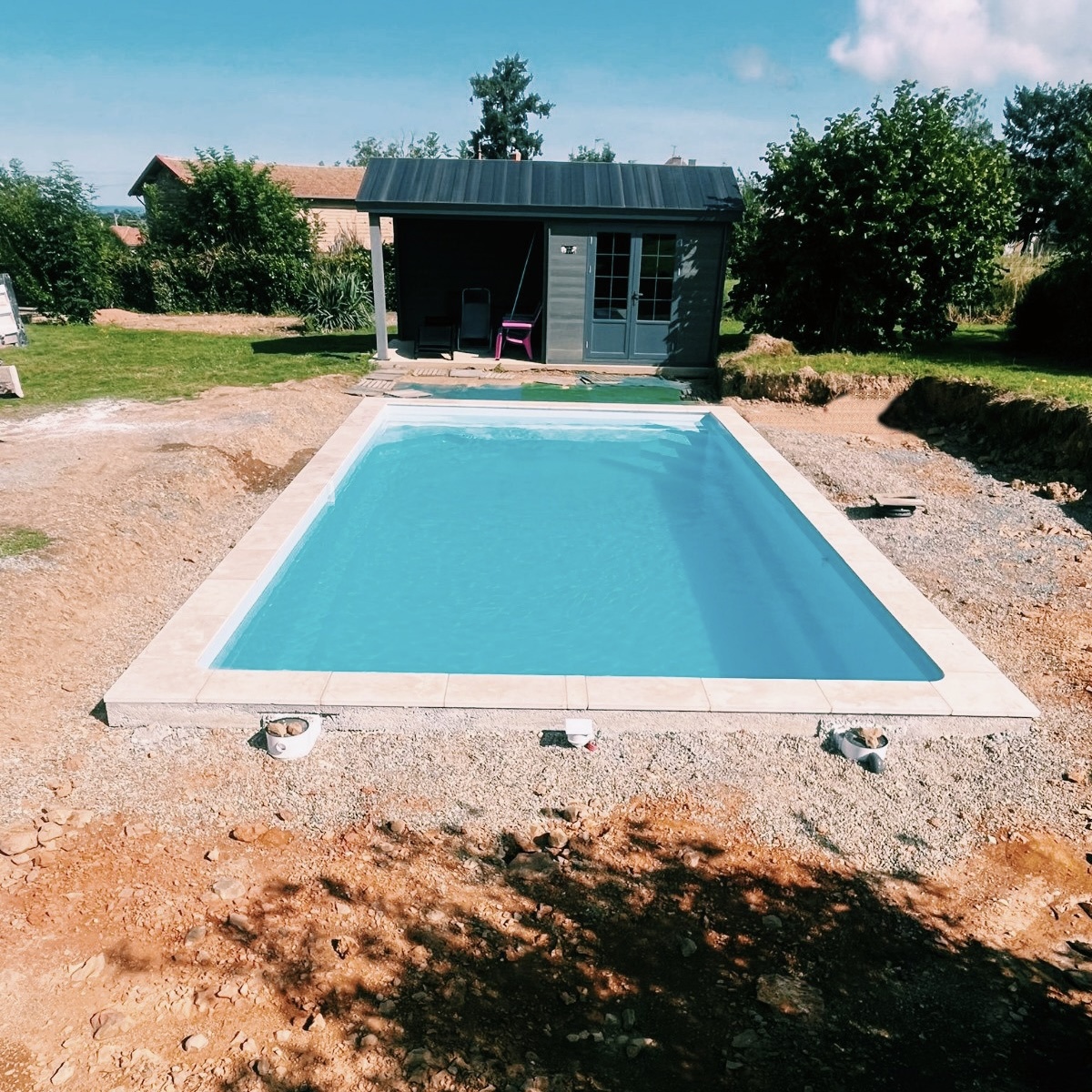 Piscine installée près d'un pool house dans un jardin