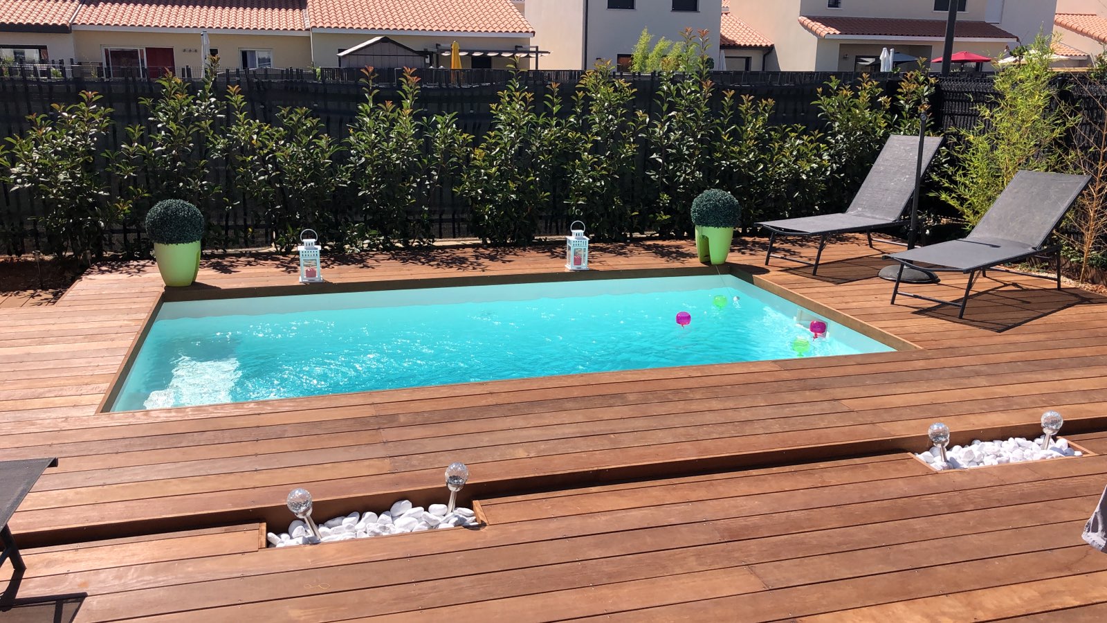 Piscine rectangulaire avec deck en bois et transats