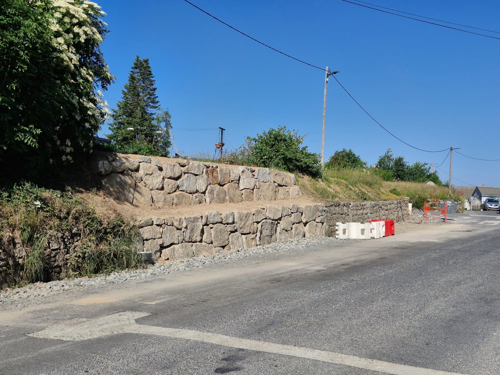 Mur d'enrochement en pierres le long d'une route en Lozère, ciel bleu