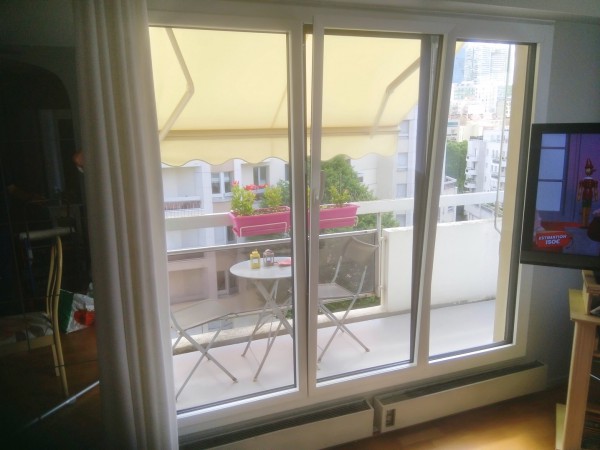 Baie vitree et store banne sur un balcon parisien avec vue sur la ville