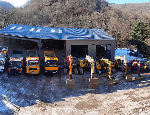 Le parc d'engins de Serre Christophe TP devant le dépôt : camions et pelles alignés